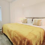 Alternate view of the super king bedroom with yellow bedding and natural light at The Oak Suite, Farnham