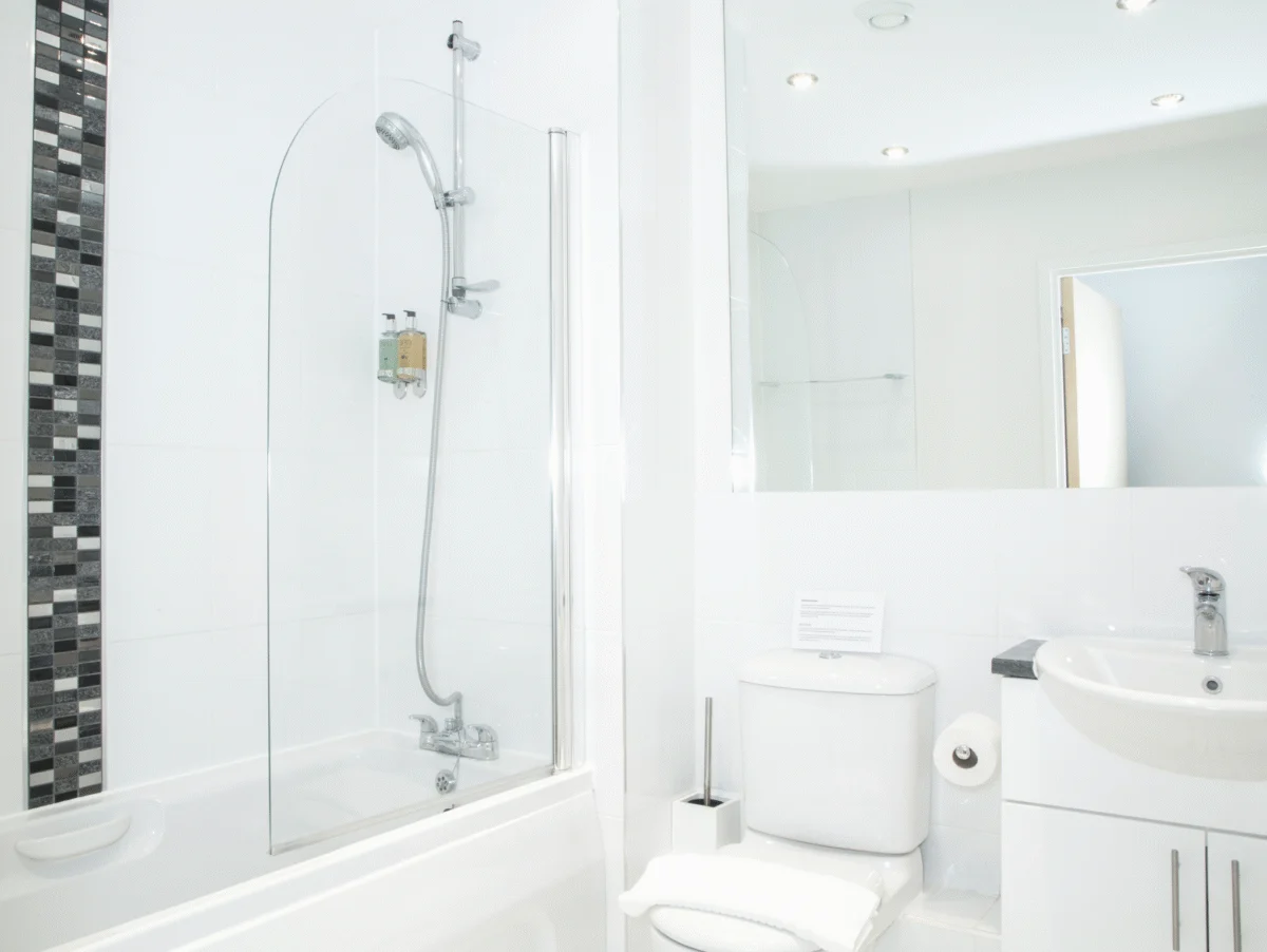 Bathroom with overhead shower, bathtub, and white interior at The Amber Suite, Woking
