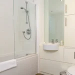Bright family bathroom with bathtub, overhead shower, sink, and toilet at The Sycamore Suite, Enterprise Place, Woking