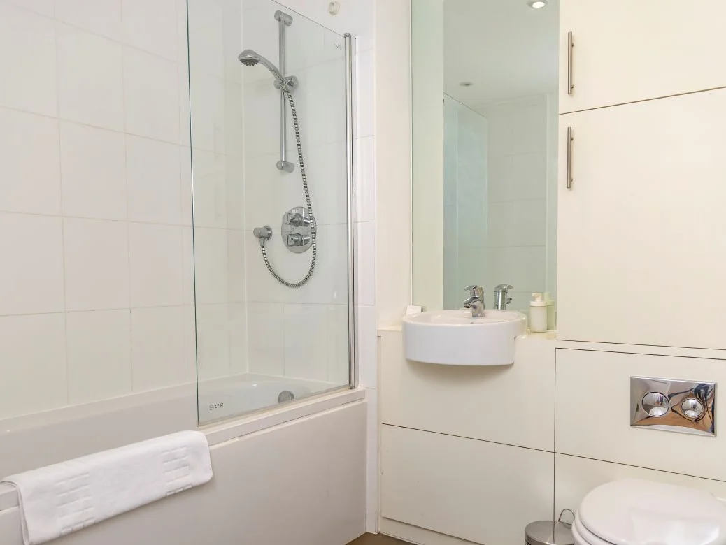 Bright family bathroom with bathtub, overhead shower, sink, and toilet at The Sycamore Suite, Enterprise Place, Woking