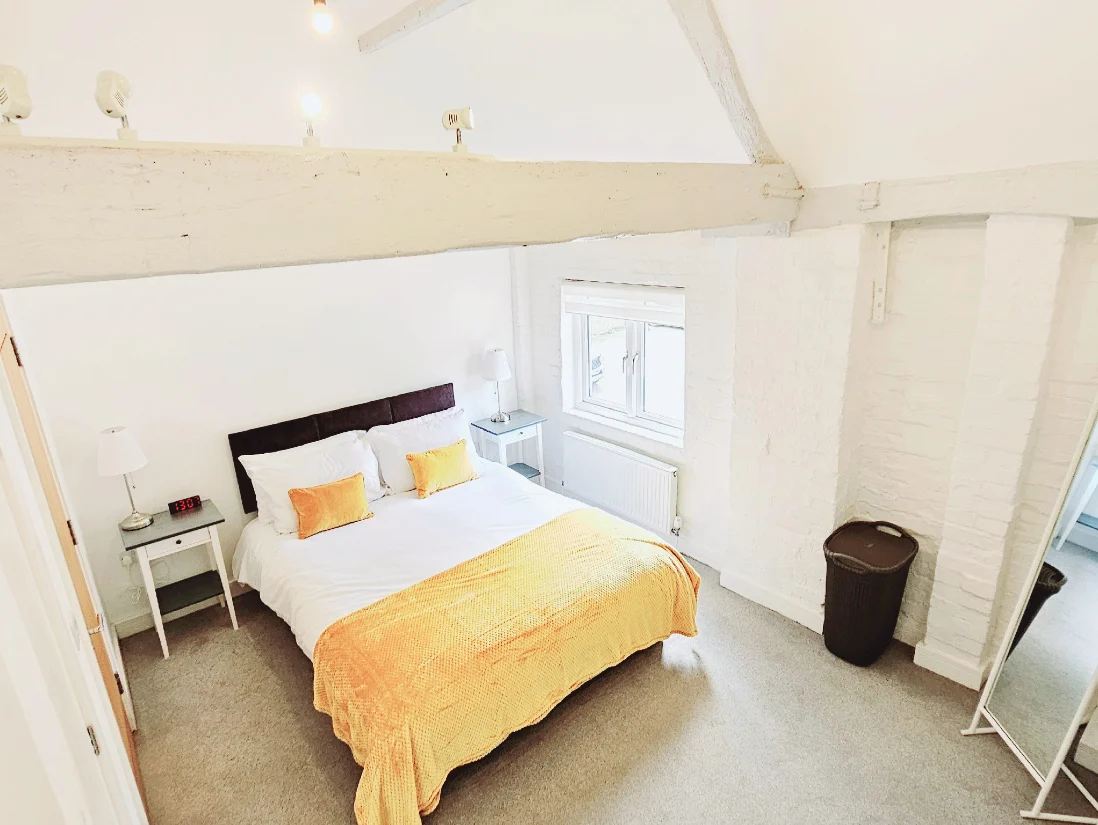 Bright master bedroom with modern furnishings and yellow bedding, The Maple Suite, Oakdale Apartments, Farnham