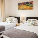 Bright twin bedroom with contemporary bedding and window view at The Amber Suite, Centrium, Woking