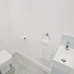 Clean white toilet and sink with modern fittings in The Oak Suite, Farnham