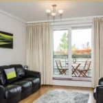 Comfortable living room with sofa, TV, and balcony access at The Amber Suite, Woking