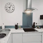 Contemporary kitchen with hob, extractor fan, and integrated appliances at The Oak Suite, Farnham