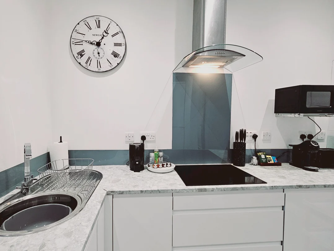 Contemporary kitchen with hob, extractor fan, and integrated appliances at The Oak Suite, Farnham