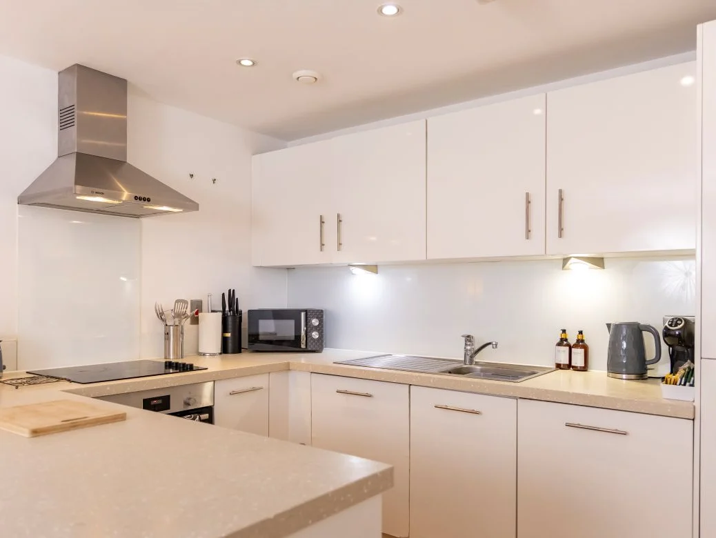 Contemporary open-plan kitchen with integrated oven and white cabinetry at The Sycamore Suite, Enterprise Place, Woking