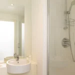 Ensuite bathroom with walk-in shower, glass screen, and wall mirror at The Sycamore Suite, Enterprise Place, Woking