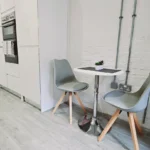 Fully fitted kitchen with oven, minimalist décor, and café-style dining table in The Oak Suite, Farnham