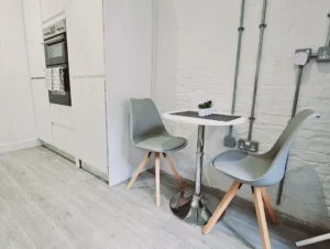 Spacious living room with dining area, modern furnishings, and a large window in The Oak Suite, Farnham