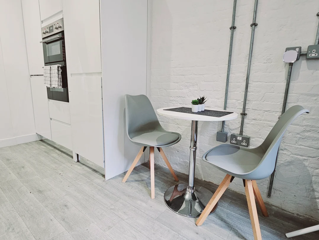 Fully fitted kitchen with oven, minimalist décor, and café-style dining table in The Oak Suite, Farnham