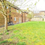 Lawned communal garden with mature trees and apartment building, The Oak Suite, Farnham