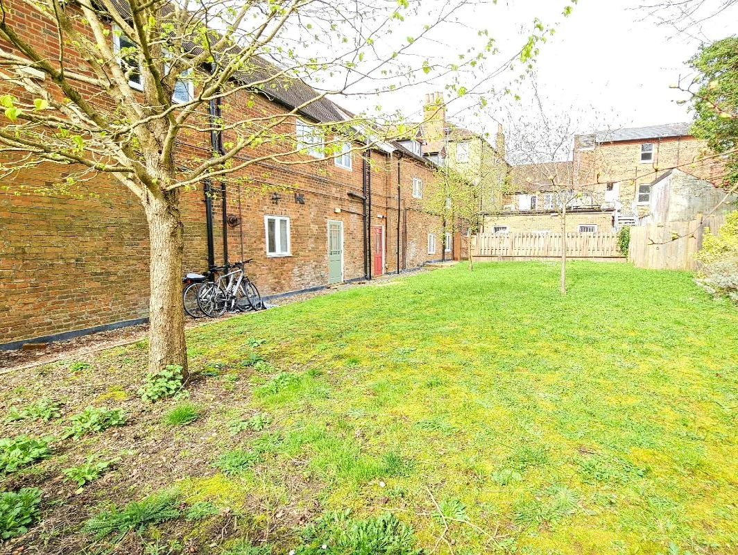 Lawned communal garden with mature trees and apartment building, The Oak Suite, Farnham