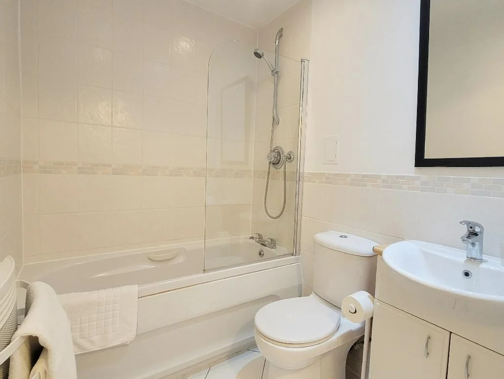 Modern bathroom with bathtub, overhead shower, toilet, and sink at The Daisy Suite, Centrium, Woking
