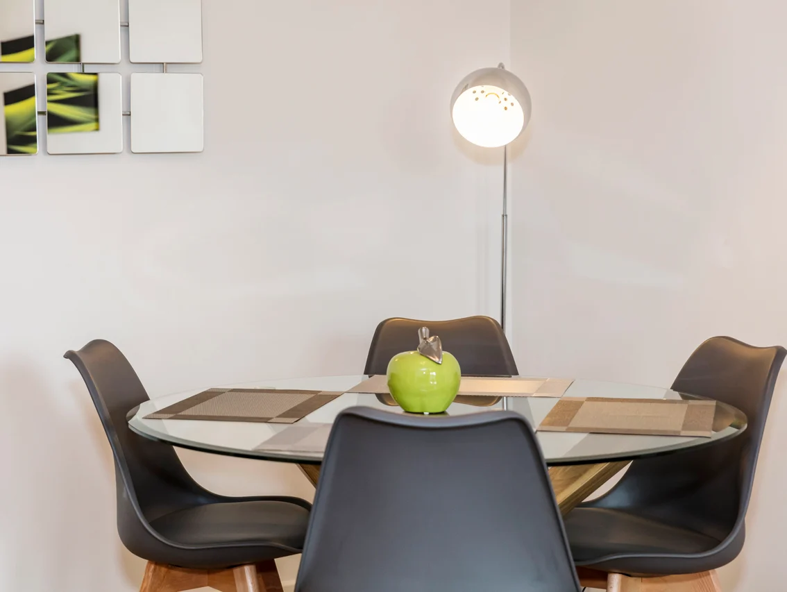 Modern dining area with table set for four and hanging lamp at The Amber Suite, Centrium, Woking