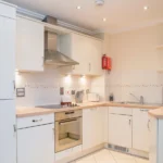 Modern kitchen with white cabinetry, integrated oven, and under-cabinet lighting at The Elm Suite, Kings Road, Reading