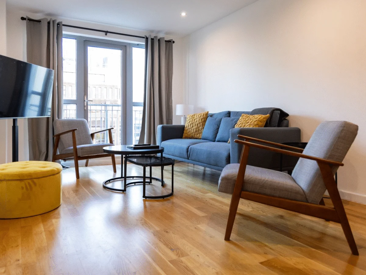 Modern living room with TV, armchairs, sofa, coffee table, and balcony view at The Sycamore Suite, Enterprise Place, Woking