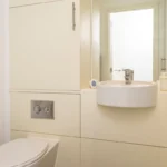Modern powder room with small sink, backlit mirror, and minimalist décor at The Sycamore Suite, Enterprise Place, Woking