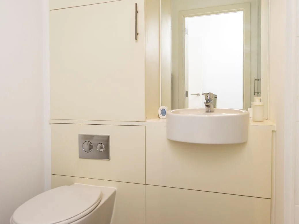 Modern powder room with small sink, backlit mirror, and minimalist décor at The Sycamore Suite, Enterprise Place, Woking