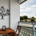 Private outdoor balcony with decorative wall art and bistro table set at The Amber Suite, Woking