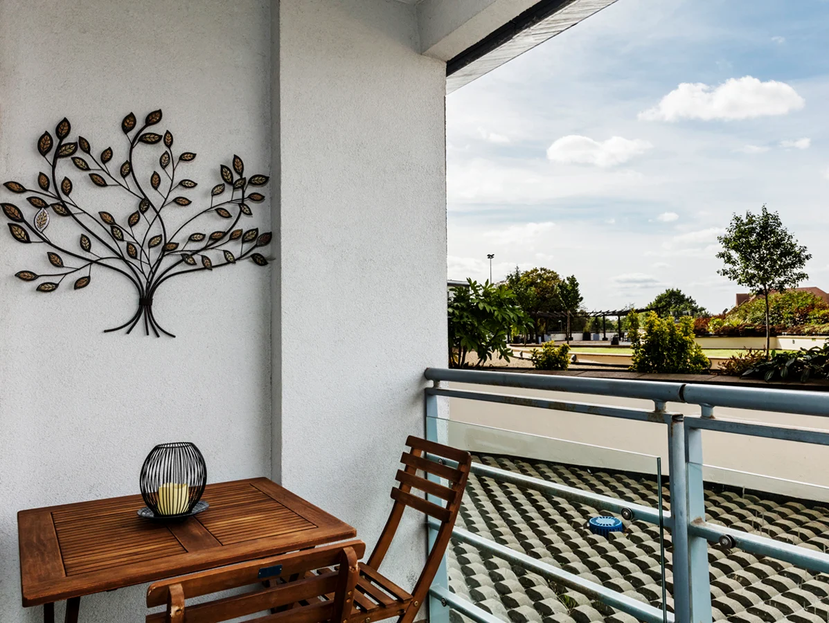 Private outdoor balcony with decorative wall art and bistro table set at The Amber Suite, Woking
