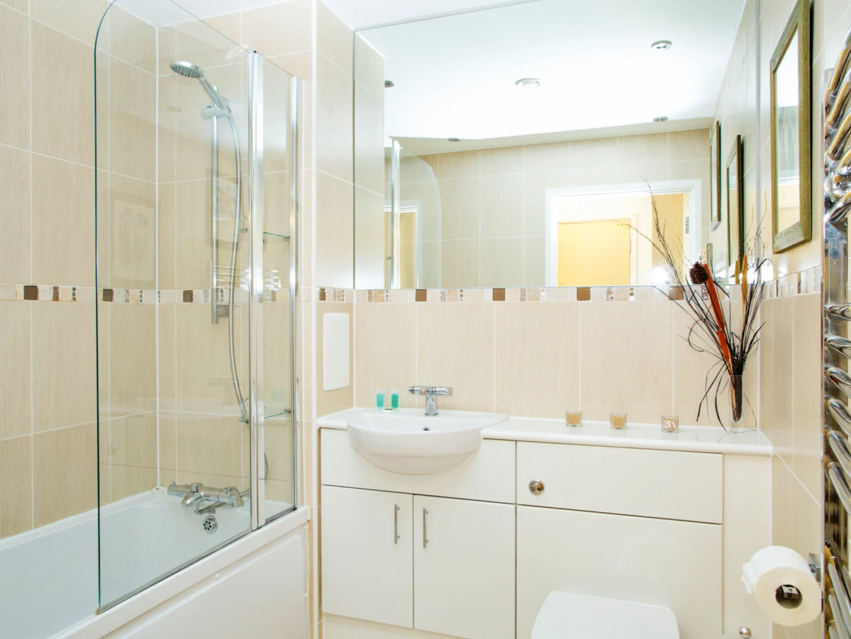 Second family bathroom with cream tiles, bath, and wide mirror at The Willow Suite, Cardinal Place, Woking