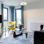 Spacious living room with TV, armchair, sofa, and large windows at The Willow Suite, Cardinal Place, Woking