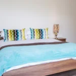 Stylish double bedroom with blue bedspread and accent cushions at The Willow Suite, Cardinal Place, Woking