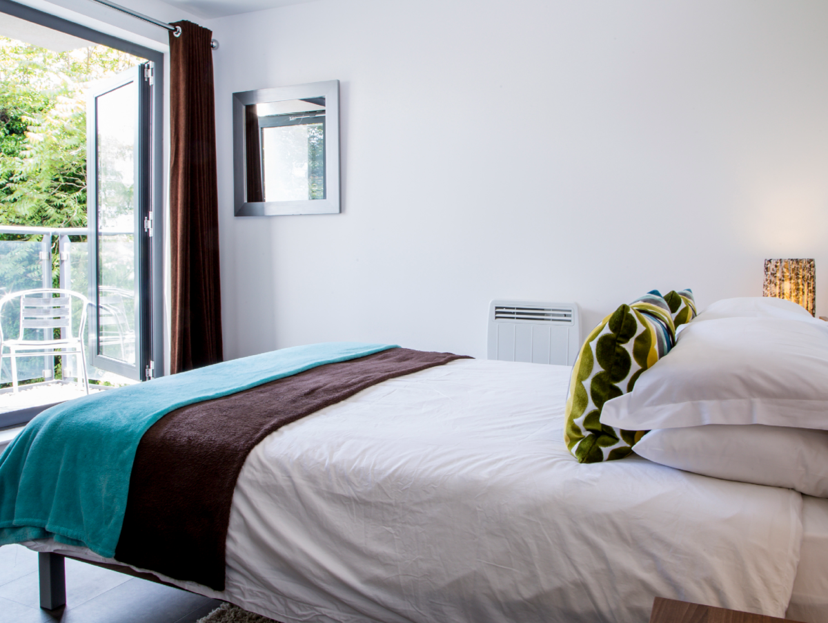 Sunlit double bedroom with balcony access and stylish decor at The Willow Suite, Cardinal Place, Woking