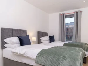 Modern living room with TV, armchairs, sofa, coffee table, and balcony view at The Sycamore Suite, Enterprise Place, Woking