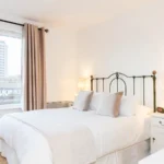 Bright twin bedroom with large windows, modern lamps, and city views at The Daisy Suite, Centrium, Woking