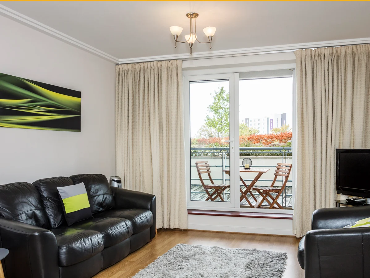 Comfortable living room with sofa, TV, and balcony access at The Amber Suite, Woking