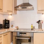 Fully fitted contemporary kitchen with integrated appliances and extractor fan at The Daisy Suite, Centrium, Woking