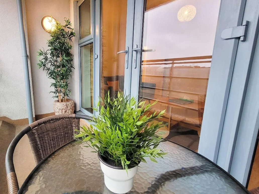 Private balcony with potted plant and outdoor seating, overlooking Centrium gardens and city, Woking