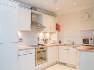 Modern kitchen with white cabinetry, integrated oven, and under-cabinet lighting at The Elm Suite, Kings Road, Reading