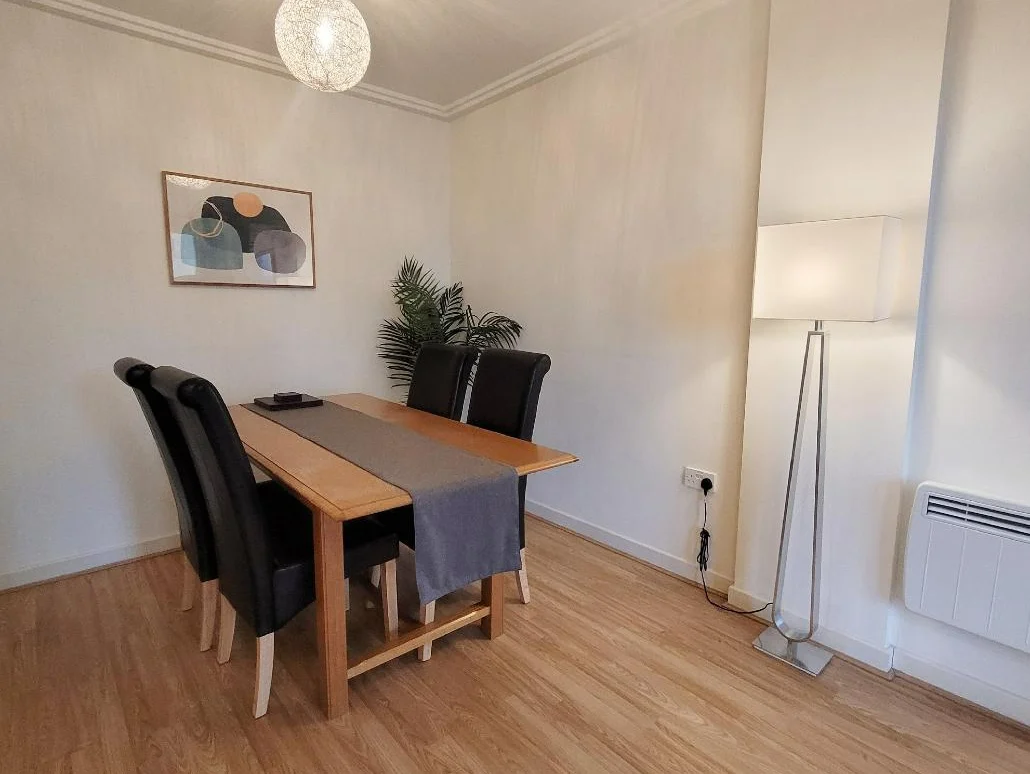 Dining area with wooden furniture and indoor plant at The Daisy Suite, Centrium, Woking